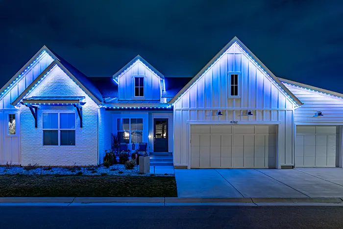 Blue permanent lights on a white farmhouse at night
