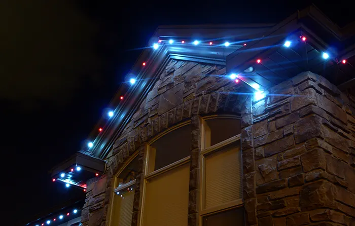Blue and white accent lights along a stone home eave