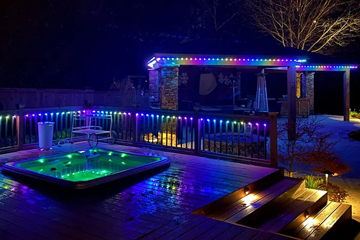 Purple permanent lights around a backyard hot tub patio
