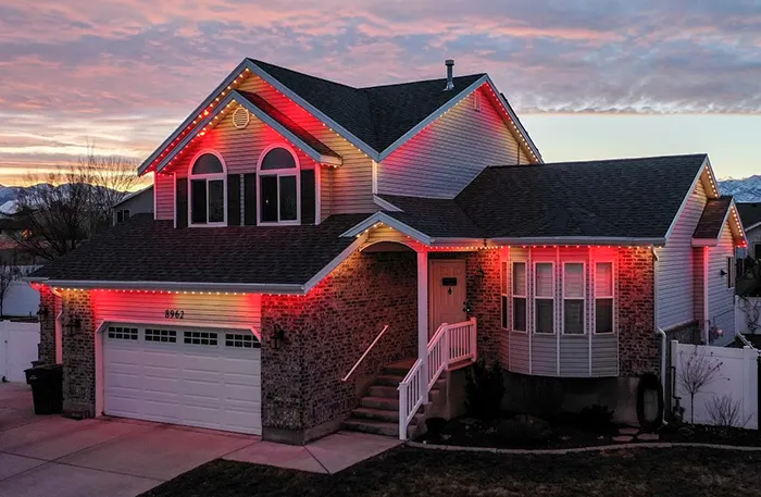 Red and orange permanent lights on a two-story home at sunset
