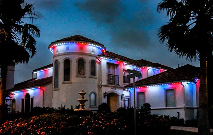 Red, white and blue permanent lights on a Mediterranean-style home