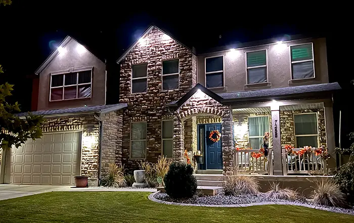 White down lights on a stone two-story home at night