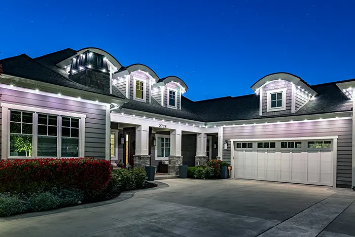 White permanent lights on a modern farmhouse at dusk