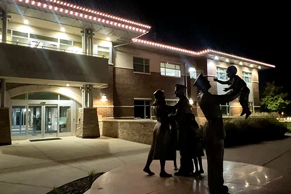 City hall with white roofline lights and a family statue