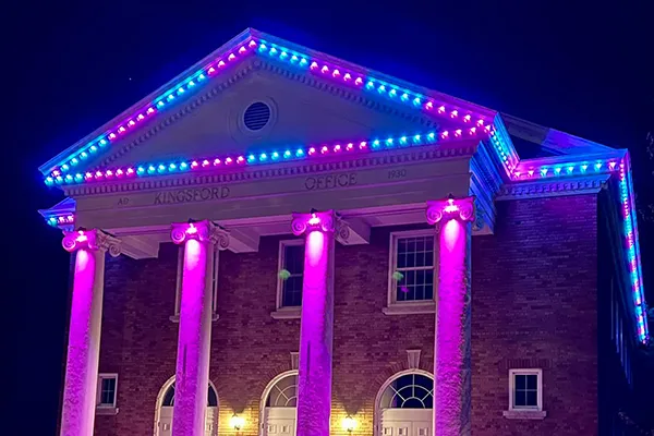Historic columned building lit in blue and pink