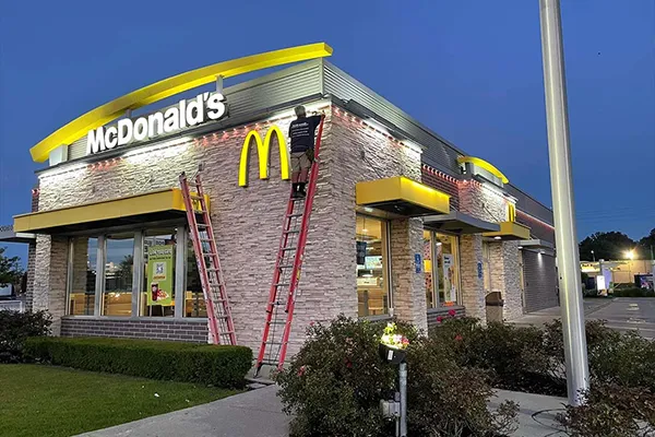 Installers on ladders adding permanent lights to a fast food restaurant
