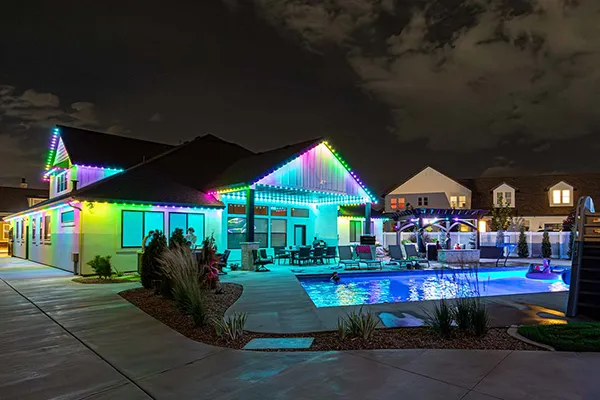 Multicolor permanent lights on a home with a backyard pool
