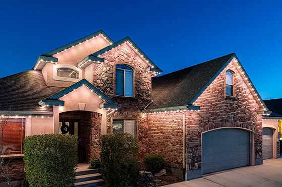 Warm accent lights on a brick home at dusk