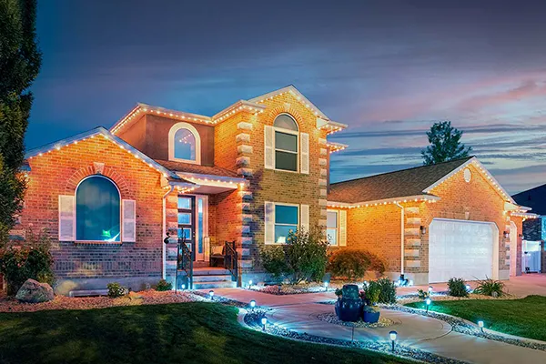Warm orange permanent lights on a brick home at dusk