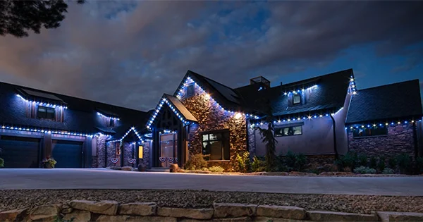 Blue permanent lights on a stone home at dusk