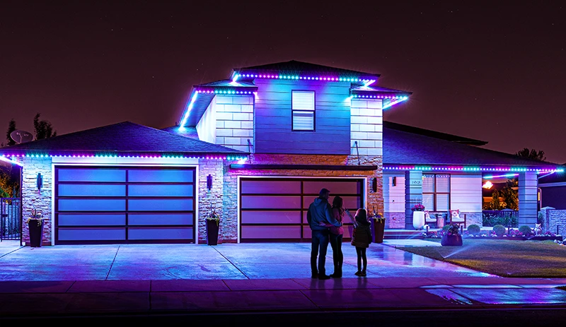 Blue and purple lights on a modern home with a family outside