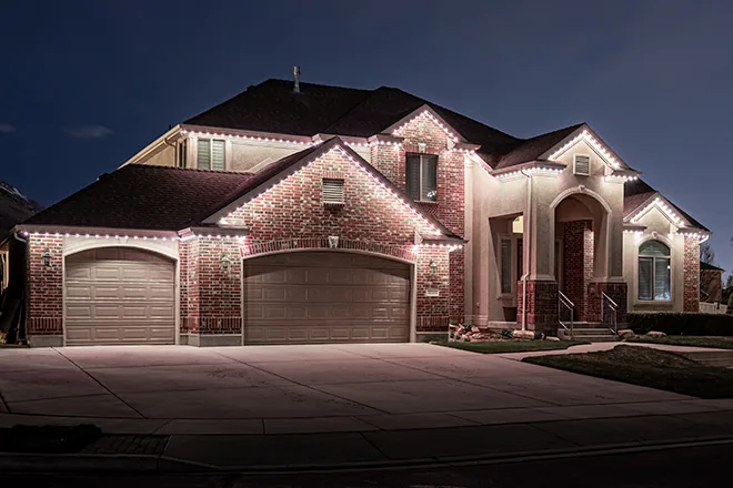 Warm white permanent lights on a brick two-story home
