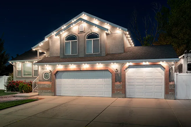 Warm white permanent lights on a stucco two-story home