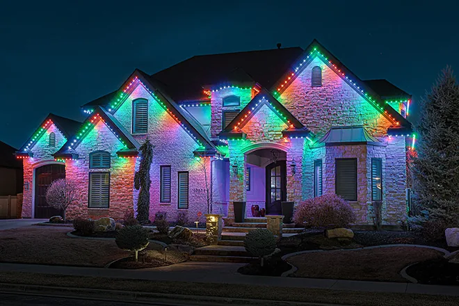 Multicolor permanent lights on a stone two-story home