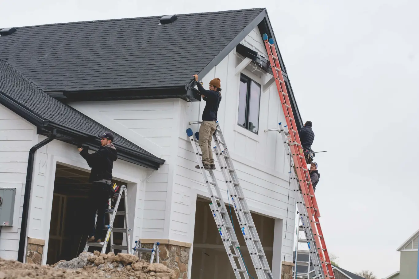 Installers on ladders adding permanent lights to a new home