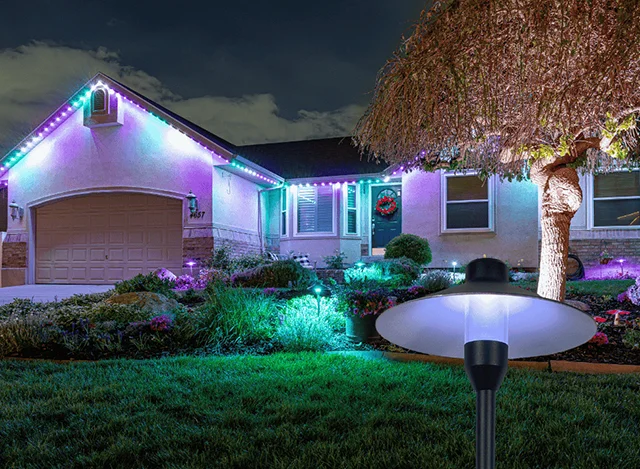 Pathway light with pink and blue roofline lights on a home