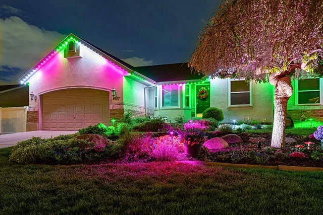Pink and green landscape and roofline lights on a ranch home
